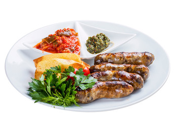 Homemade sausages with potatoes and sauce. On a white plate