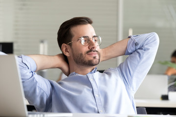 Relaxed confident business man taking break from work on laptop for mind relief holding hands...