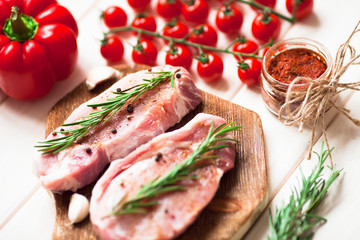 Fresh raw pork on the cutting board with ingredients for cooking. Food, flat lay, recipes and nutrition concept. Top view. Close up.