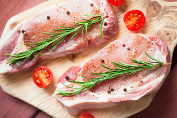 Fresh raw pork on the cutting board with ingredients for cooking. Food, flat lay, recipes and nutrition concept. Top view. Close up.