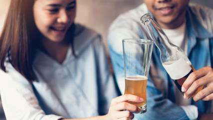 Friends are smiling, happy partying in the bar and talking and clinking bottles with beverages.