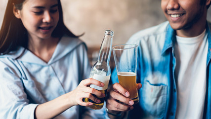Friends are smiling, happy partying in the bar and talking and clinking bottles with beverages.