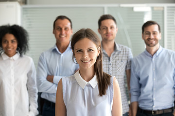 Fototapeta na wymiar Young female leader, company employee or office worker smiling looking at camera, happy successful millennial professional manager business coach posing with diverse team staff members, portrait