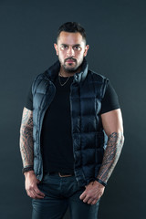 Bearded man posing with tattoos. Macho unshaven brutal wear vest. Masculinity and fashion concept....