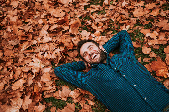 Young man lying down on the ground covered in autumn leaves