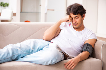 Fototapeta premium Young man measuring blood pressure at home