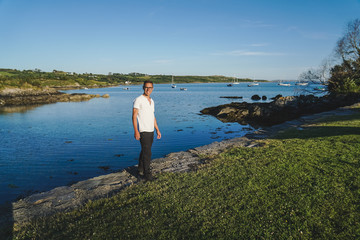 Fototapeta na wymiar portrait of a man in a white polo t-shirt and glasses on the background of the bay and yachts