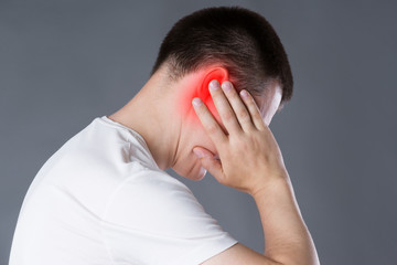 Man with earache, ear pain on gray background
