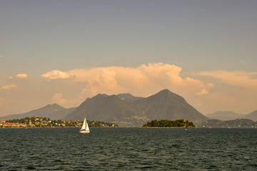 Lake view with sailboat, island and coast at sunset, Maggiore Lake, Piedmont, Italy