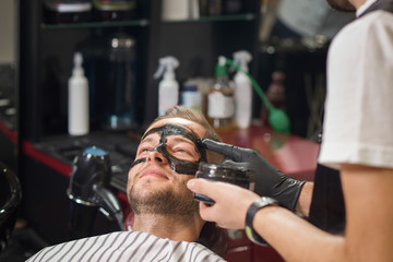 Barber putting black mask against black dots on male face