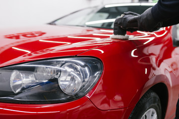 Car detailing - Man with orbital polisher in repair shop polishing car. Selective focus.