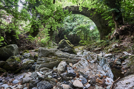  Stone ruins of the Byzantine bridge in a dense forest in Greece.