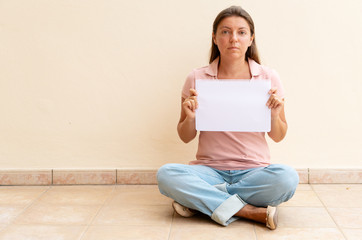 Woman sitting and holding empty white paper with copy space