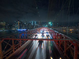 Traffic cars over the Brooklyn Bridge. Against the night cityscape NYC