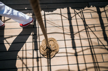 Sailor in white trousers and red shoes walking on a deck of a vintage sailing ship.