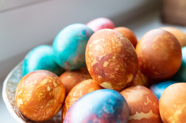 Closeup of colourful dyed easter eggs in a ceramic bowl.