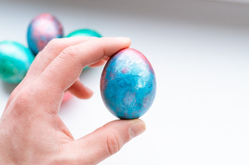 Top view of holding a shiny blue and red easter egg on a white background. 