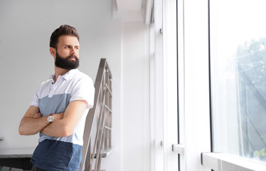 Young bearded man near window. Working in office