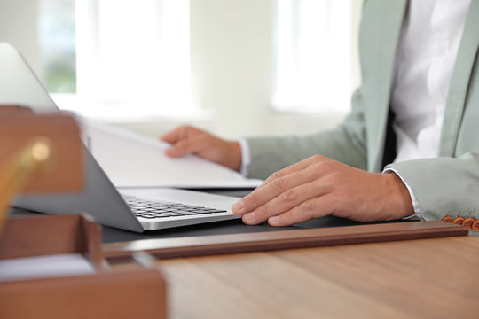 Male notary working with laptop at table in office, closeup