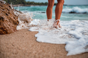 Woman walking on the beach barefoot during sunset