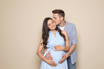 Pregnant woman and her husband on color background. Space for text