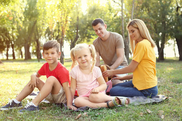Naklejka na ściany i meble Happy family having picnic in park on sunny day
