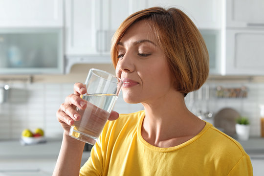 Woman drinking clean water from glass in kitchen