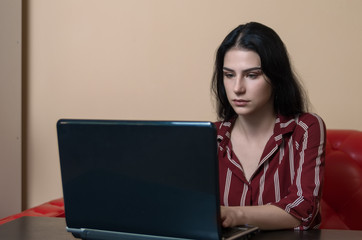 Teenager girl doing her work on laptop with neutral face