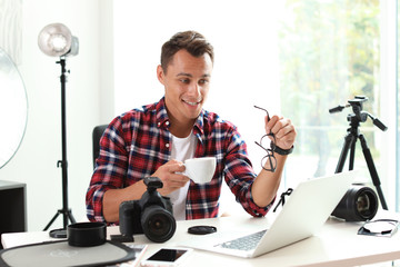 Portrait of photo blogger with cup of coffee and laptop at home. Online broadcast