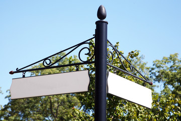 Blank vintage two-way street sign with tree in the background.