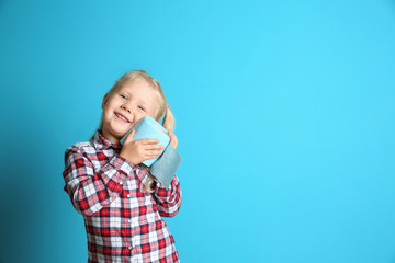 Cute little girl holding toilet paper roll on color background. Space for text