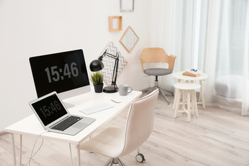 Stylish workplace with computers on table in room