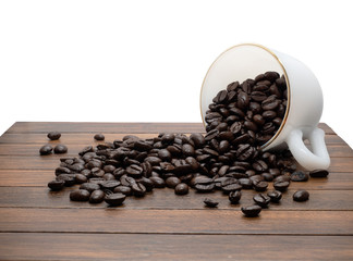 arabica coffee beans spilling out of a glass mug on a  wooden table