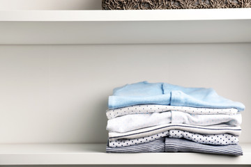 Stacked baby clothes on shelf. Space for text
