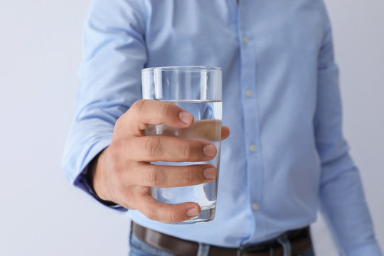 Man holding glass of pure water on white background, closeup