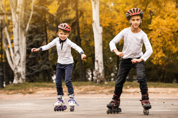 Happy children roller skating in autumn park
