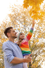 Father and his cute daughter spending time together in park. Autumn walk