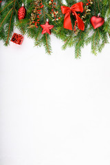 Fototapeta na wymiar Spruce branches decorated with red ornaments and red barberry berries on a white background.