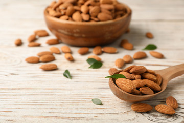 Tasty organic almond nuts in spoon on table. Space for text