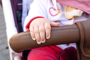 little beautiful baby sitting in the pram hand close-up