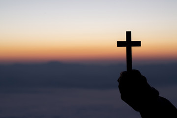 Silhouette of cross in human hand, the background is the sunrise., Concept for Christian,...