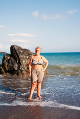 Fototapeta na wymiar Portrait of a woman posing near a rock on the foreshore at beach