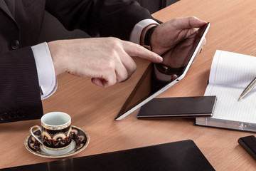 The hands of a businessman with an electronic book at the desk