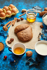 Ready for next step raw gingerbread dough placed among various ingredients. Christmas baking concept. Placed on blue background. View from above.