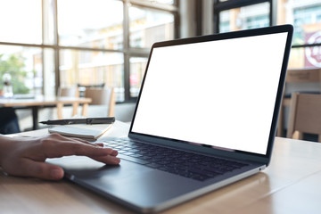 Mockup image of  a hand using and touching laptop touchpad with blank white desktop screen while sitting in office