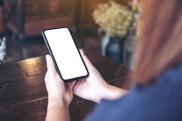 Mockup image of a woman holding black mobile phone with blank desktop screen in cafe