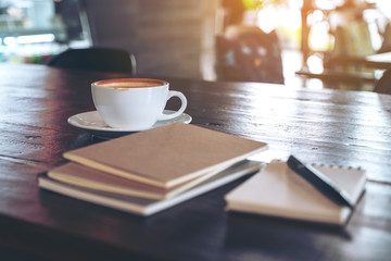 Notebooks, pen and coffee cup on wooden table in cafe