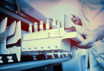 a female scientist near the analyzer in a medical microbiological laboratory. Equipment for...
