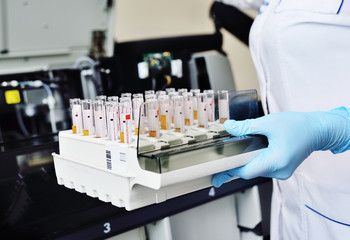 A scientist in a laboratory places test tubes with blood or urine in the container of a thermal...