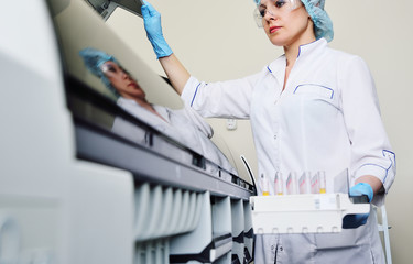 a female scientist near the analyzer in a medical microbiological laboratory. Equipment for...